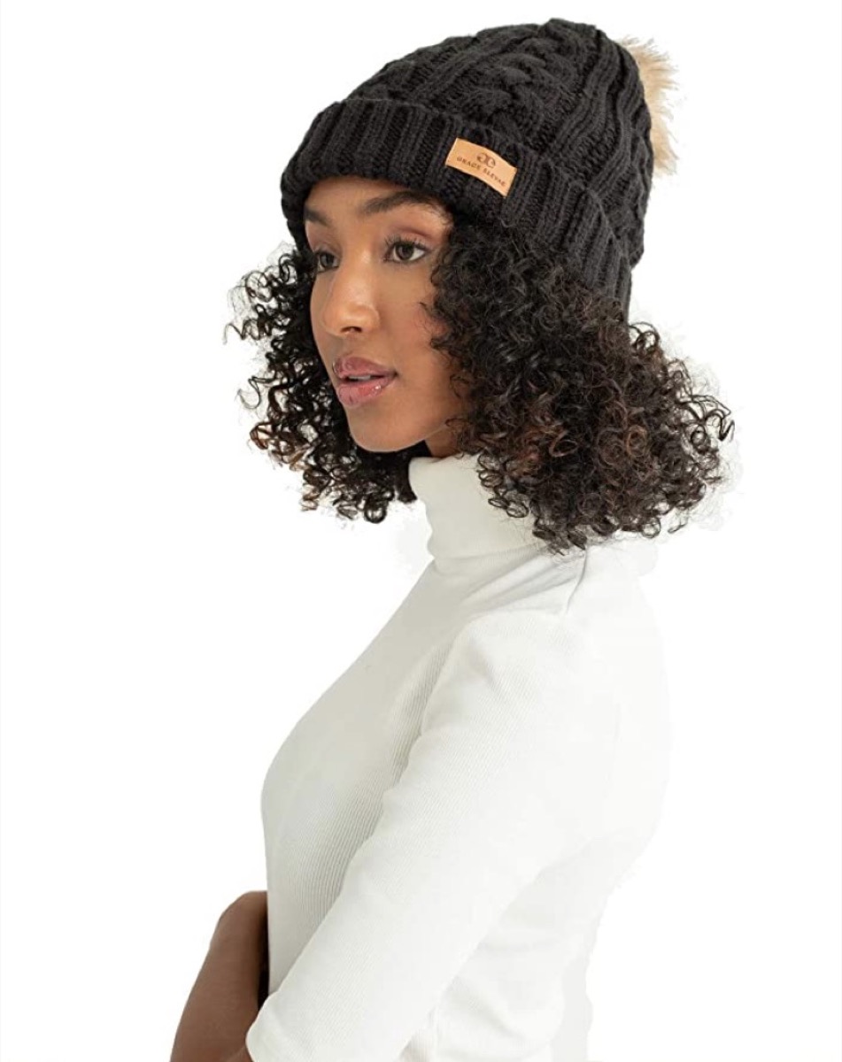 black woman in black knit hat with fur pompom