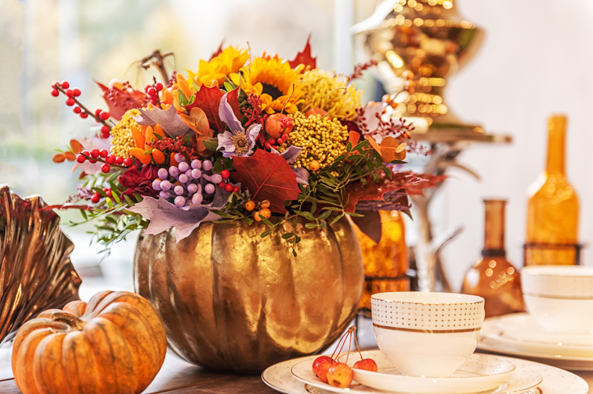 autumn flower composition in a pumpkin vase on a table decorated with pumpkins