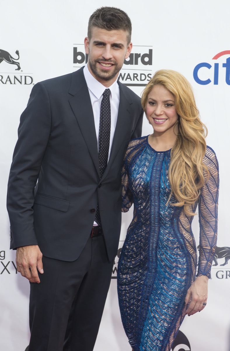 Gerard Pique wears a black suit and Shakira wears a blue dress at the Billboard Music Awards in 2014