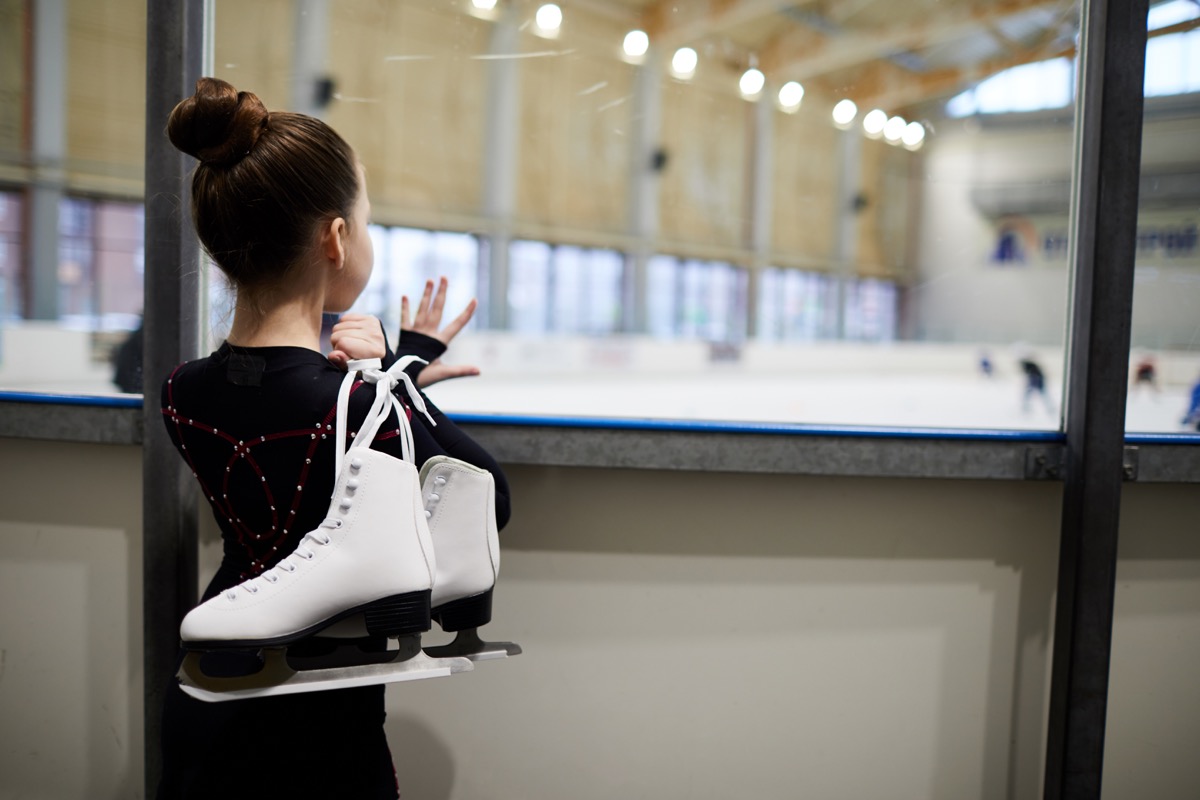 Young ice skating girl looking at the rink