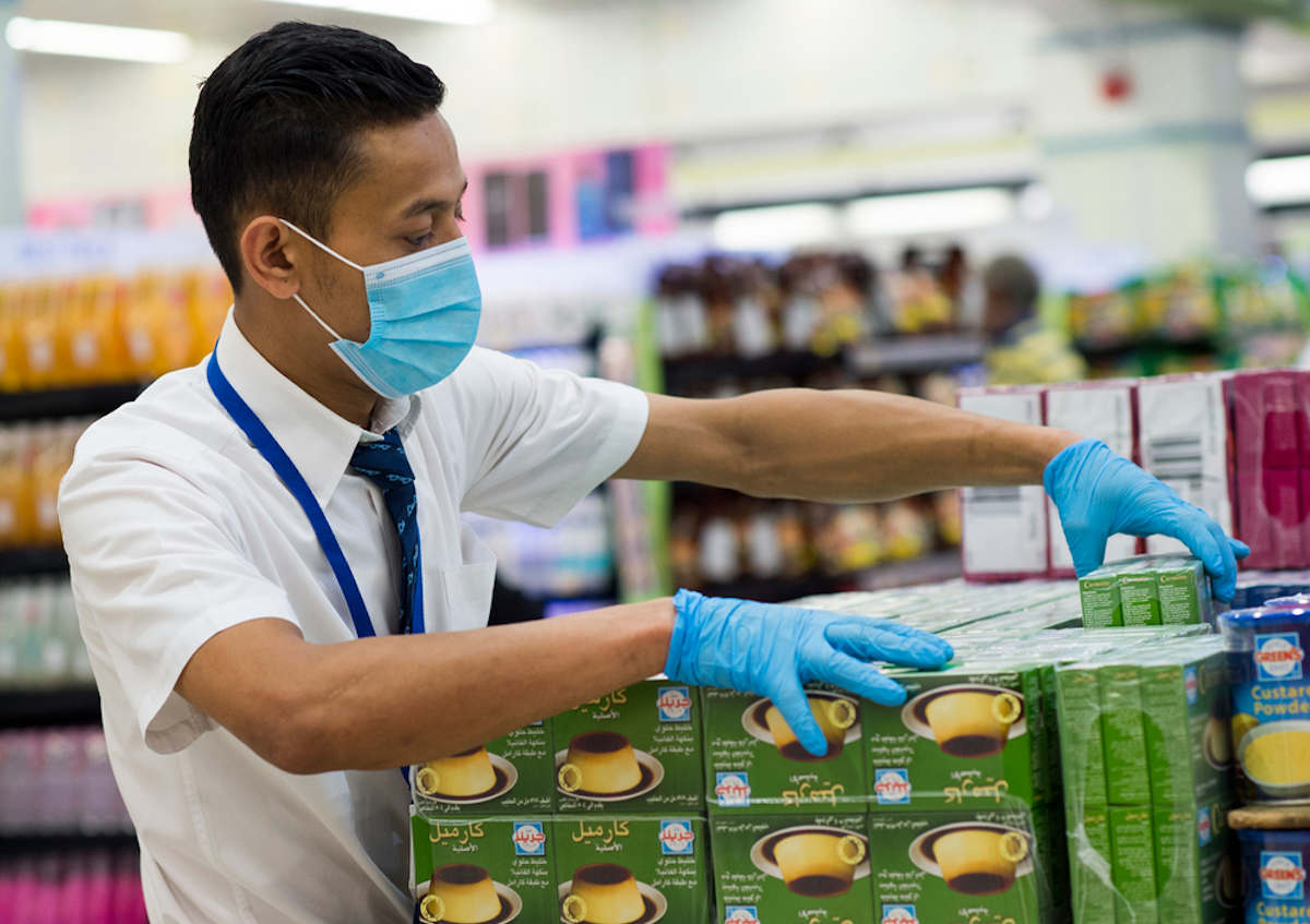 Store employee wearing a face mask due to the Covid-19 Pandemic while stacking boxes