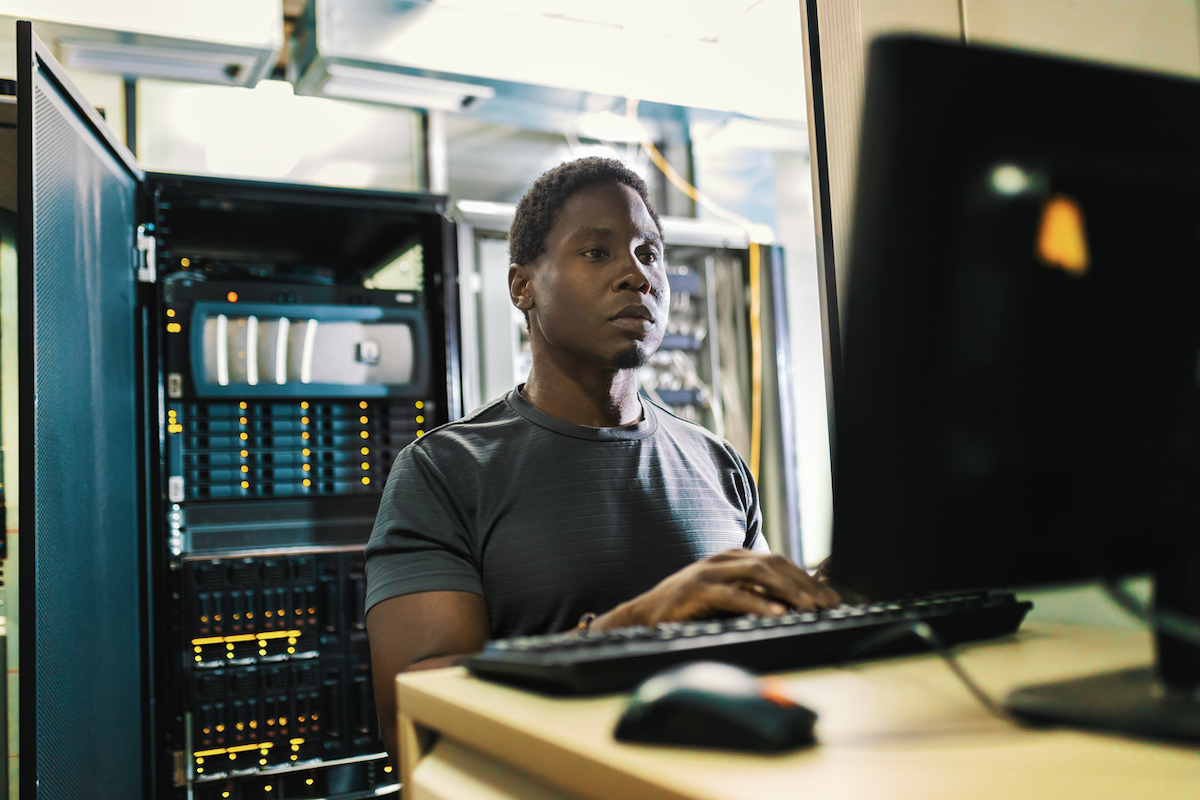 Black man is working in data center with laptop