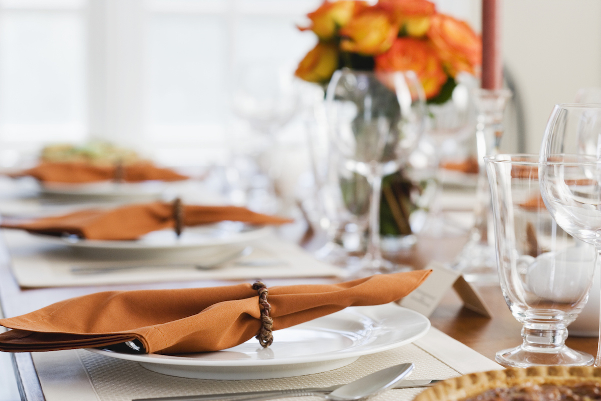 fine china with orange napkins on Thanksgiving dinner table