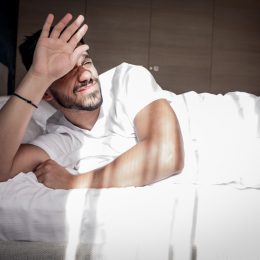 A man wakes up in bed under stress