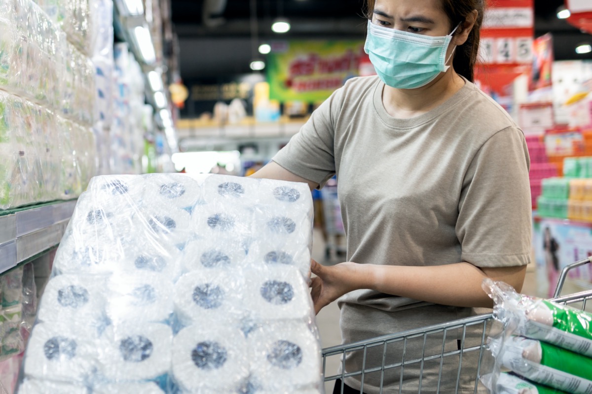 woman wearing mask and buying toilet paper