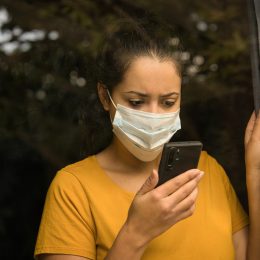 young woman wearing a face mask looking at her smartphone