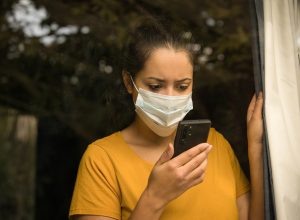 young woman wearing a face mask looking at her smartphone