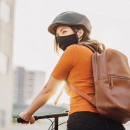 Young adult riding a bicycle through the city wearing face mask against COVID-19