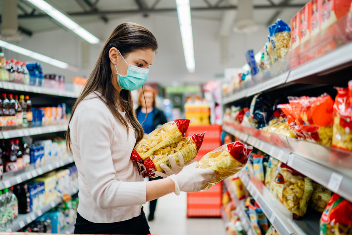 woman buying pasta while wearing mask at supermarket