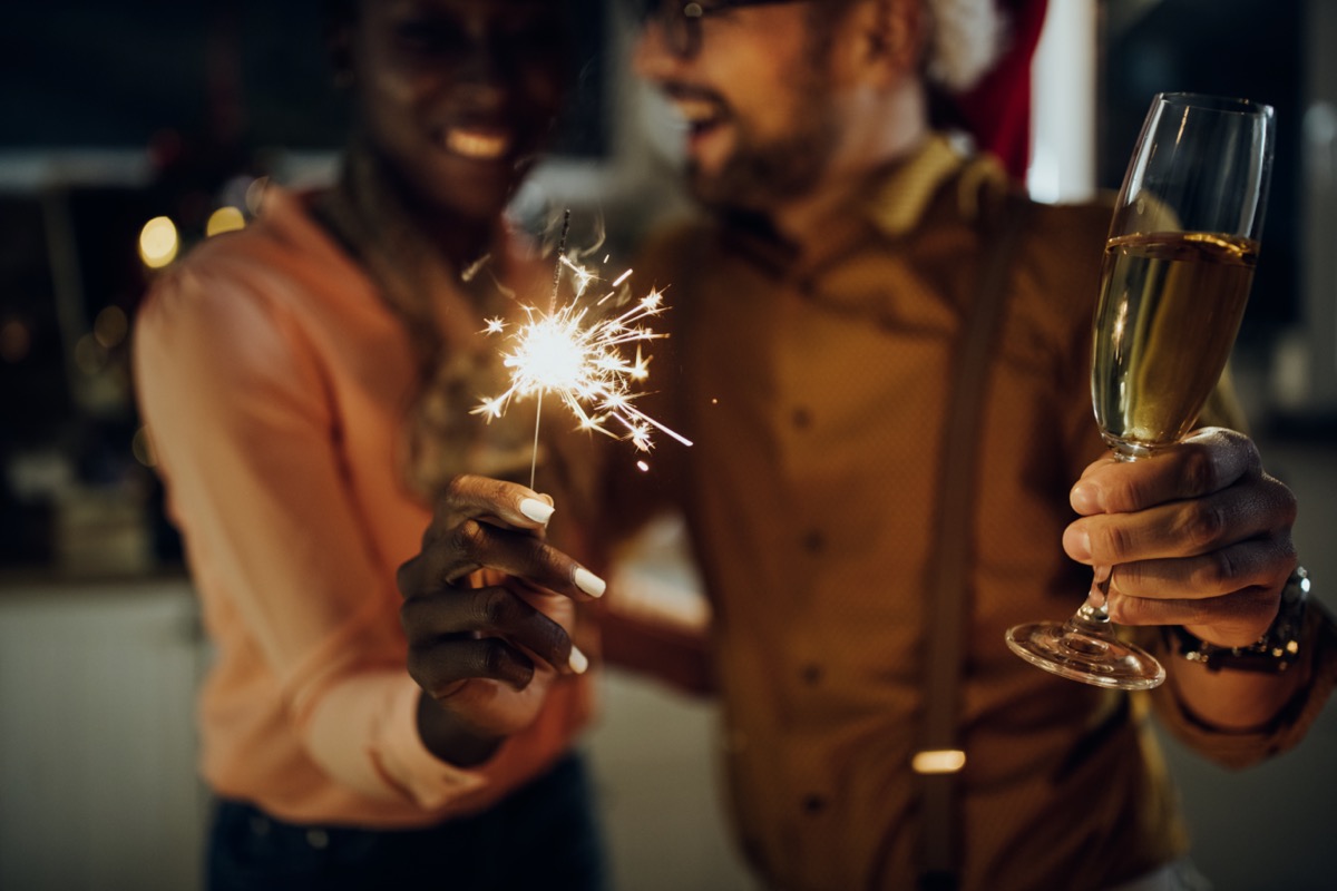 Man and woman holding sparkler and champagne glass on New Year's