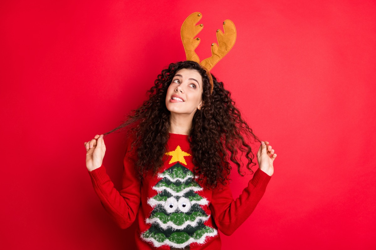 Young woman in Christmas tree sweater and reindeer antlers