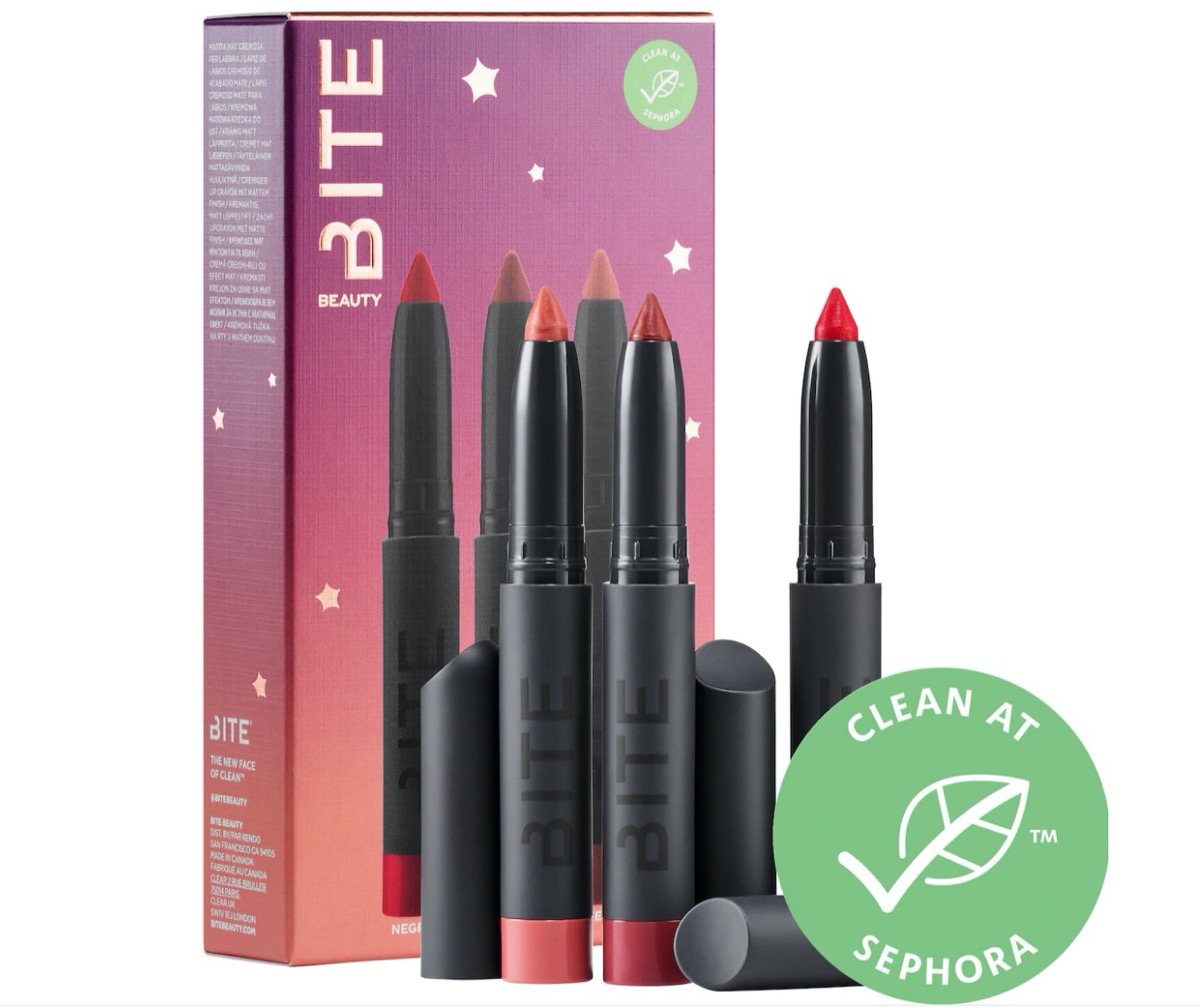 set of three lipstick crayons with tops off in front of box with purple and orange or pink sunset