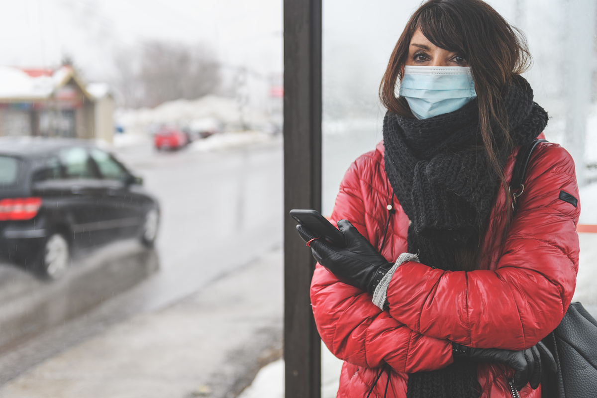 Woman waiting for the bus, wearing protective mask to protect from covid-19