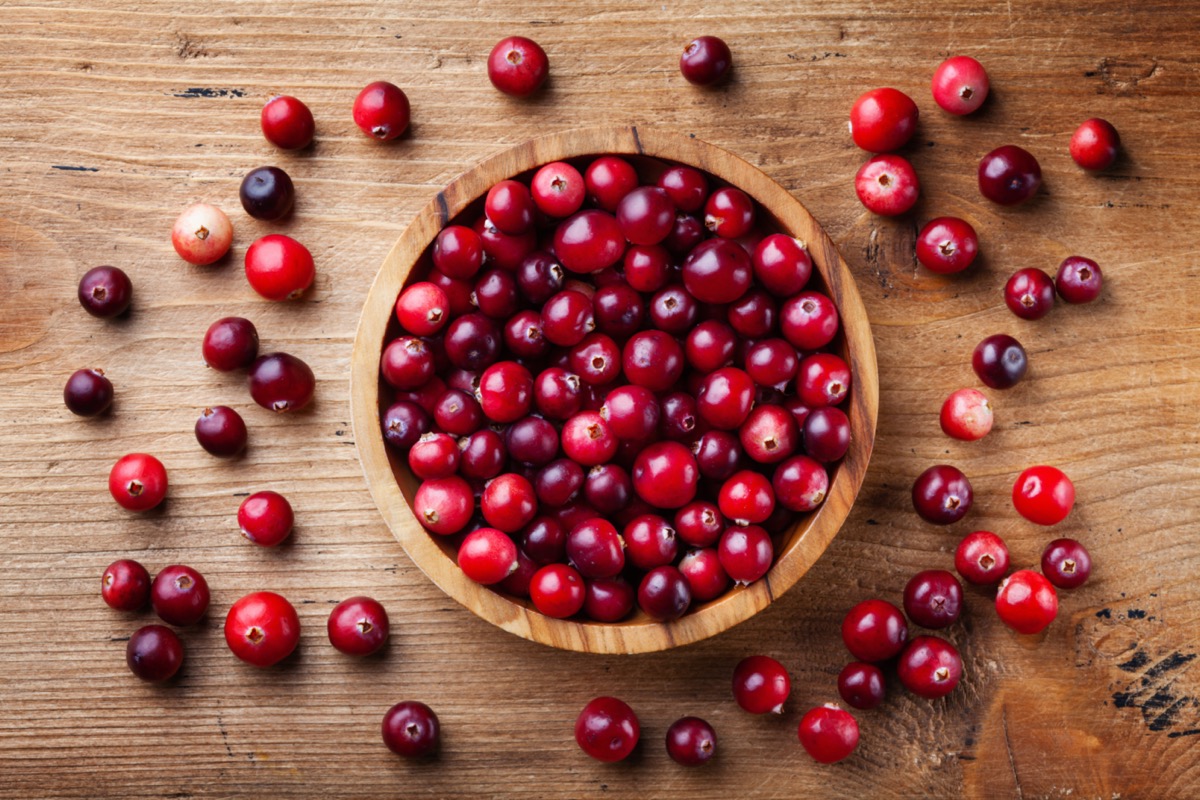 Cranberries in wooden bowl on wood surface