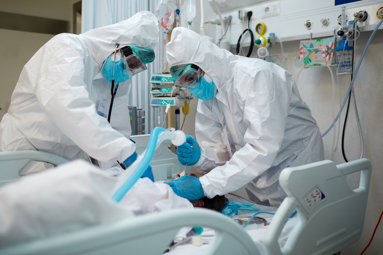 Two doctors wearing protective gear intubate a COVID patient in the ICU.