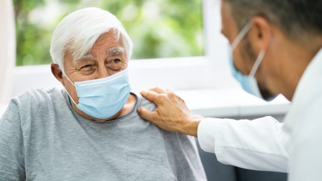 doctor talking to elderly patient wearing mask