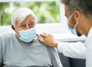 doctor talking to elderly patient wearing mask