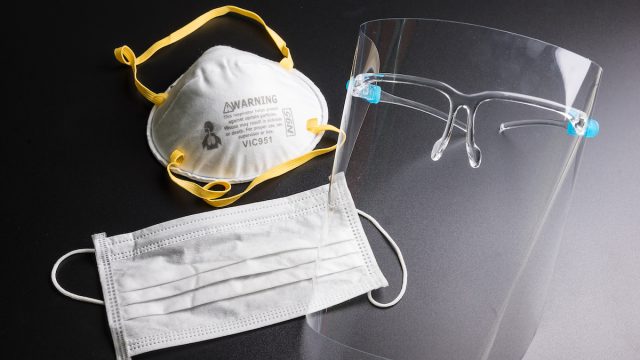 Face shield, surgical mask, and N95 mask on a black background