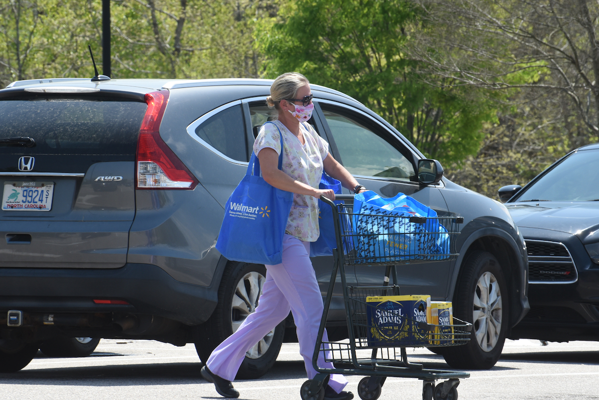 A healthcare worker wearing scrubs and a face mask leaves a grocery store amid the COVID-19 pandemic.