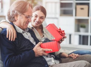 young girl giving father gift in red box