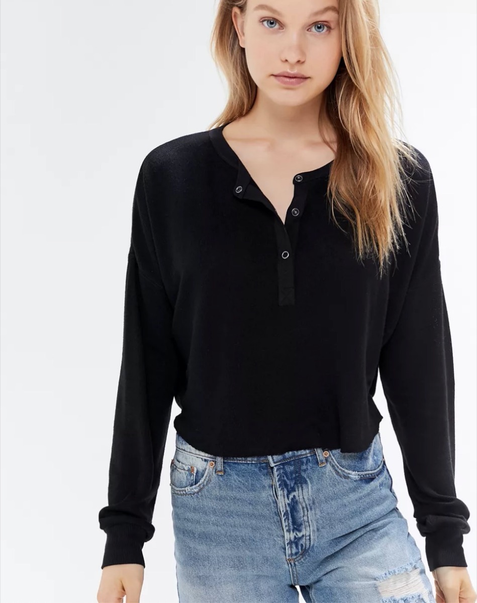 young woman wearing black snap-up henley top and jeans