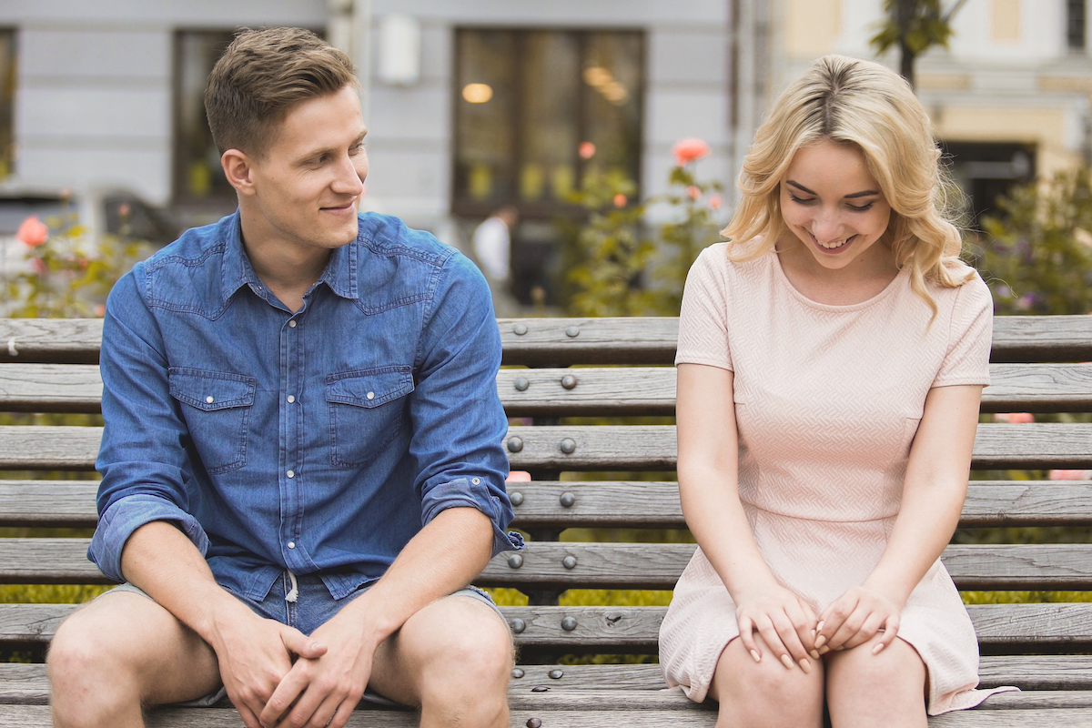 young man flirting with blonde woman on bench