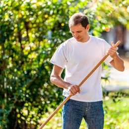 middle-aged man raking in yard