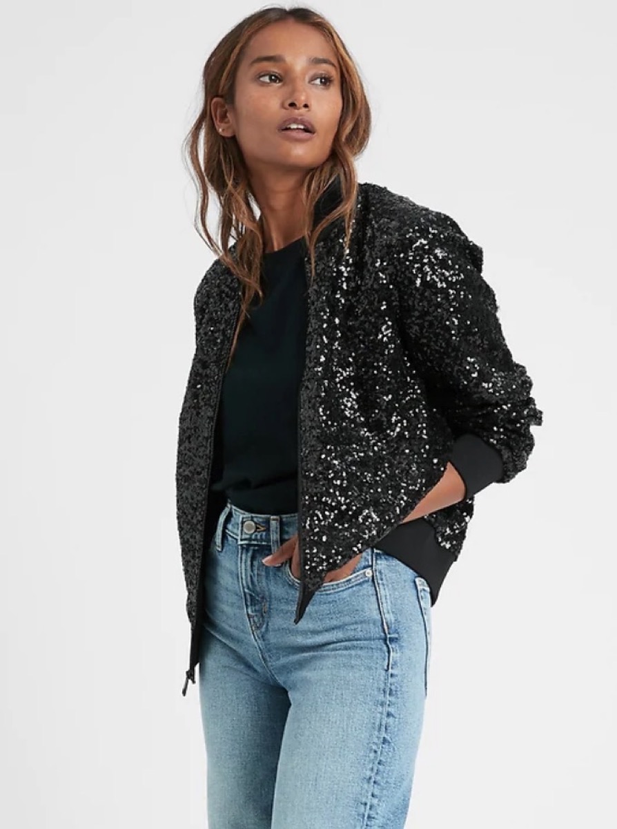 young woman wearing black sequin jacket and jeans