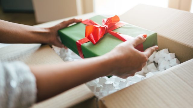 Close up of woman hands opening parcel with present box.