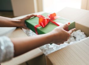 Close up of woman hands opening parcel with present box.