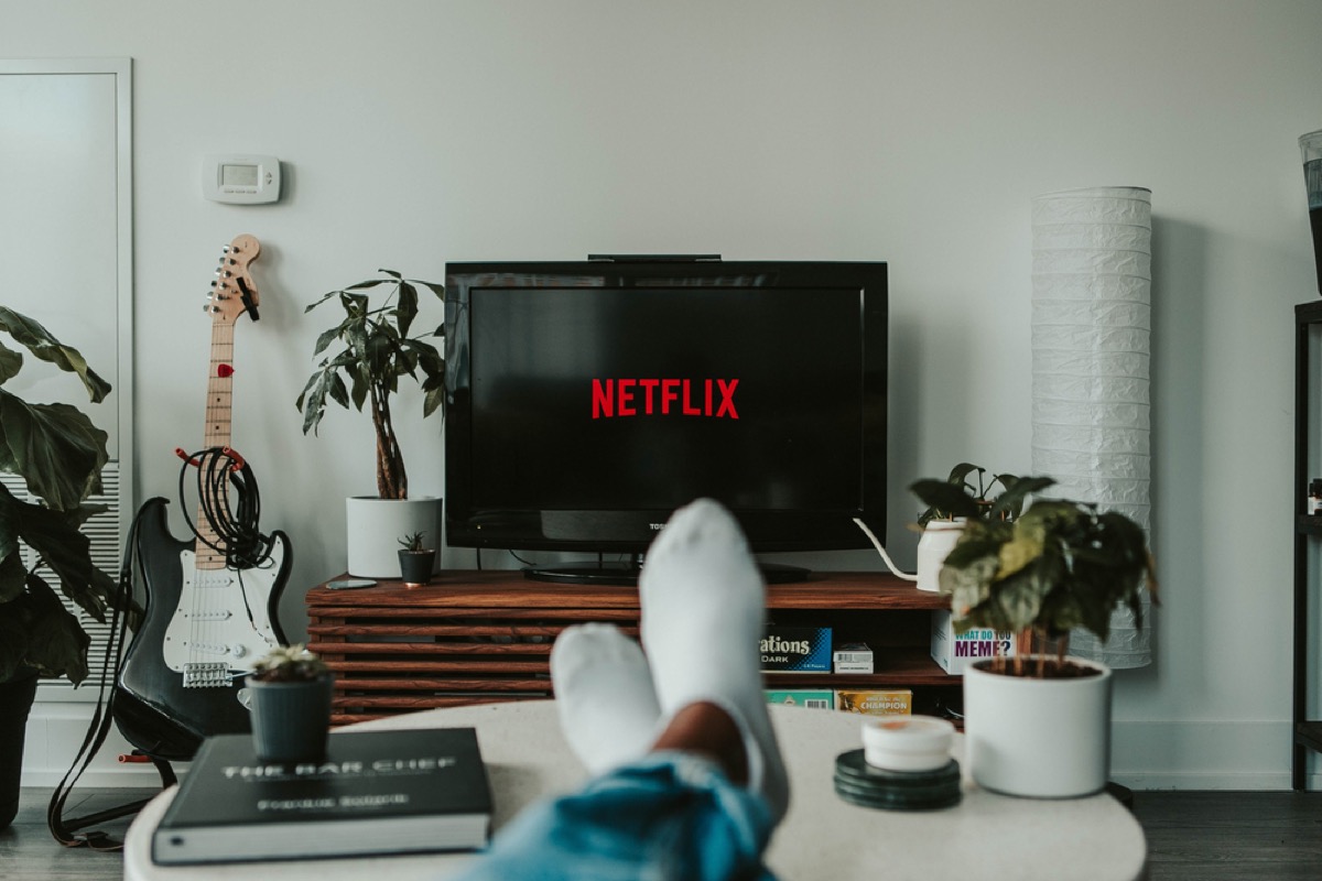 man's feet on the table while netflix is on the tv in front of him