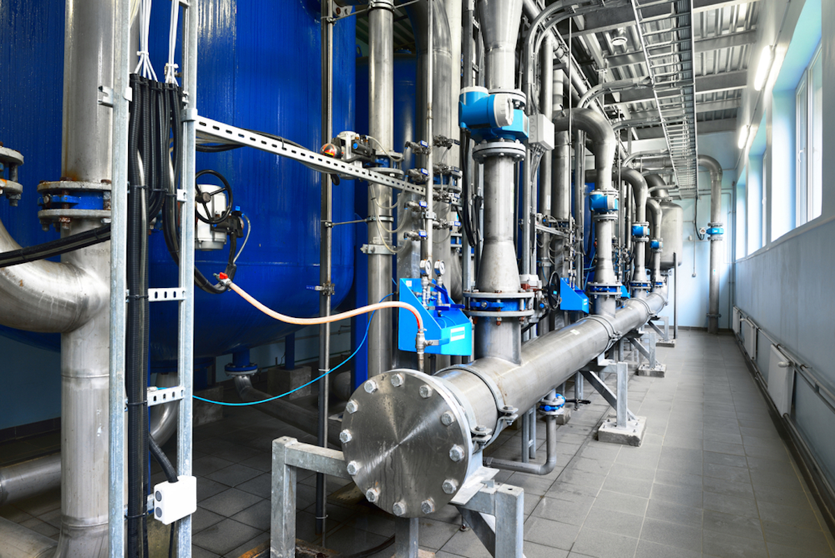 Large industrial water treatment and boiler room. Shiny steel metal pipes, blue pumps and valves, close-up.