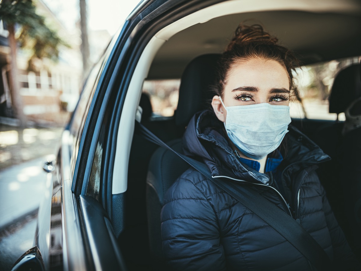Young woman wearing disposable face mask while riding in car. Mask is Disposable Earloop Face Mask with Filters against Bacteria.