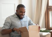 young man looking excited while opening cardboard box