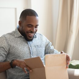 young man looking excited while opening cardboard box