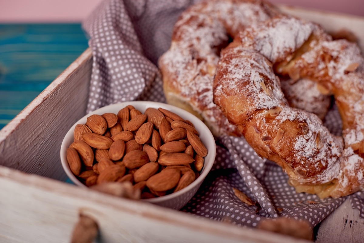 almond kringle and dish of almonds on wooden tray
