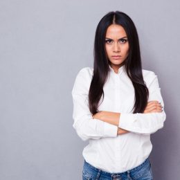 woman in a white blouse with her arms cross and an angry look on her face