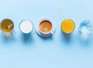 Tea, Milk, Coffee, Orange Juice, and Water on Table with Top View on Blue Background