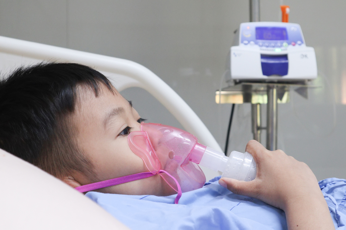 Boy using Inhaler mask for treatment in hospital.