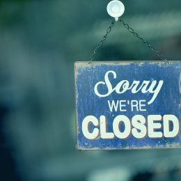 Close-up on a blue closed sign in the window of a shop displaying the message "Sorry we are closed"