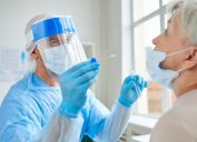 doctor in face shield and ppe giving older woman covid test