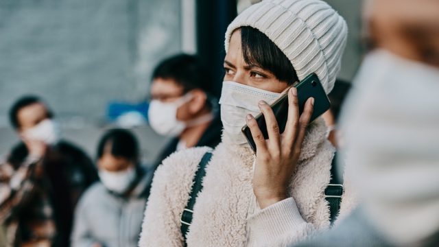 Shot of a young woman using a smartphone and wearing a mask while travelling in a foreign city