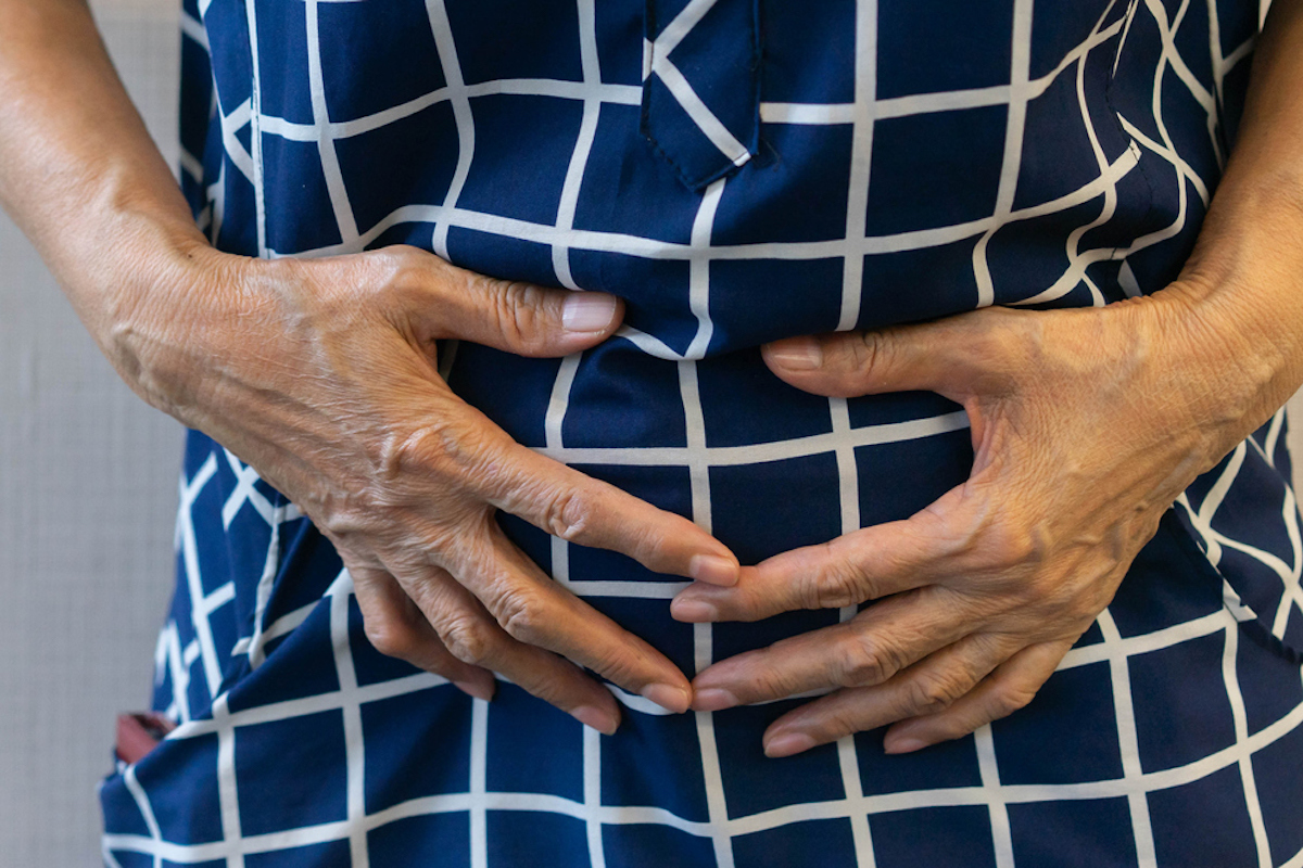 close up senior woman using hand to touch stomach after feeling pain