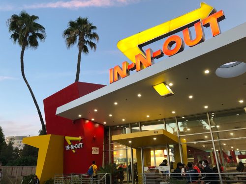 An In-N-Out Burger location at sunset with palm trees out front.