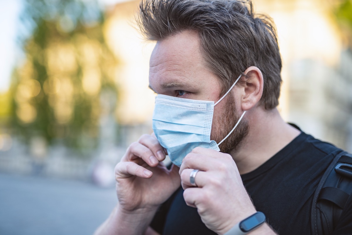 Man Putting On Face Mask In The City To Prevent Getting Coronavirus, COVID-19