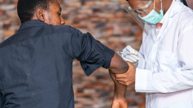 young man in gray shirt getting covid vaccine