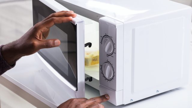 man putting food in white microwave
