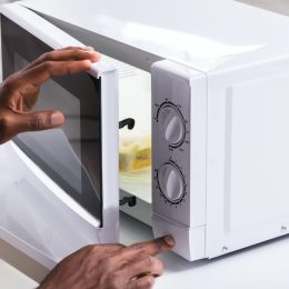man putting food in white microwave