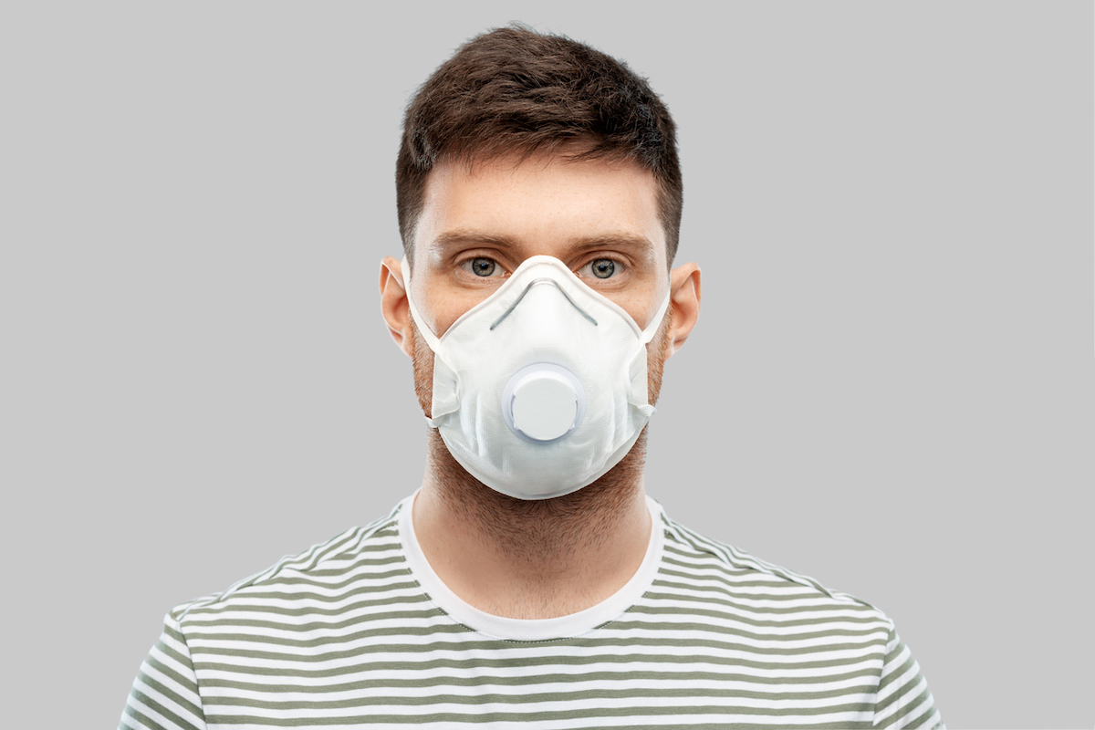 man in protective mask or respirator with valve over grey background