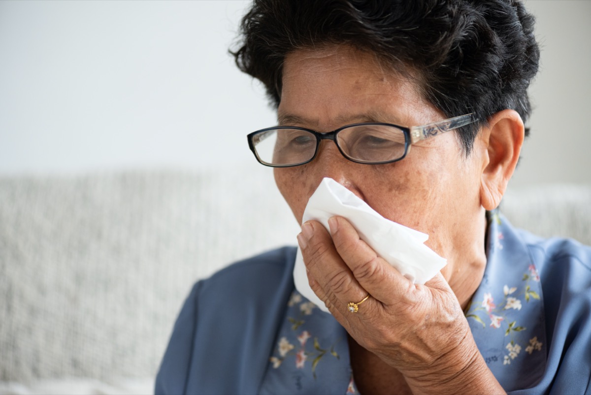 older woman coughing into tissue